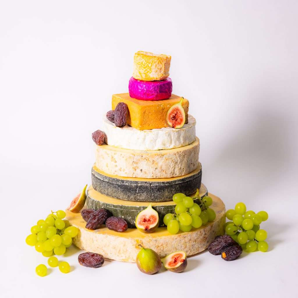 A Rinds & Vines wedding cheese cake: a tall tower of artisan cheese tiers dressed with green grapes, fresh figs and dates